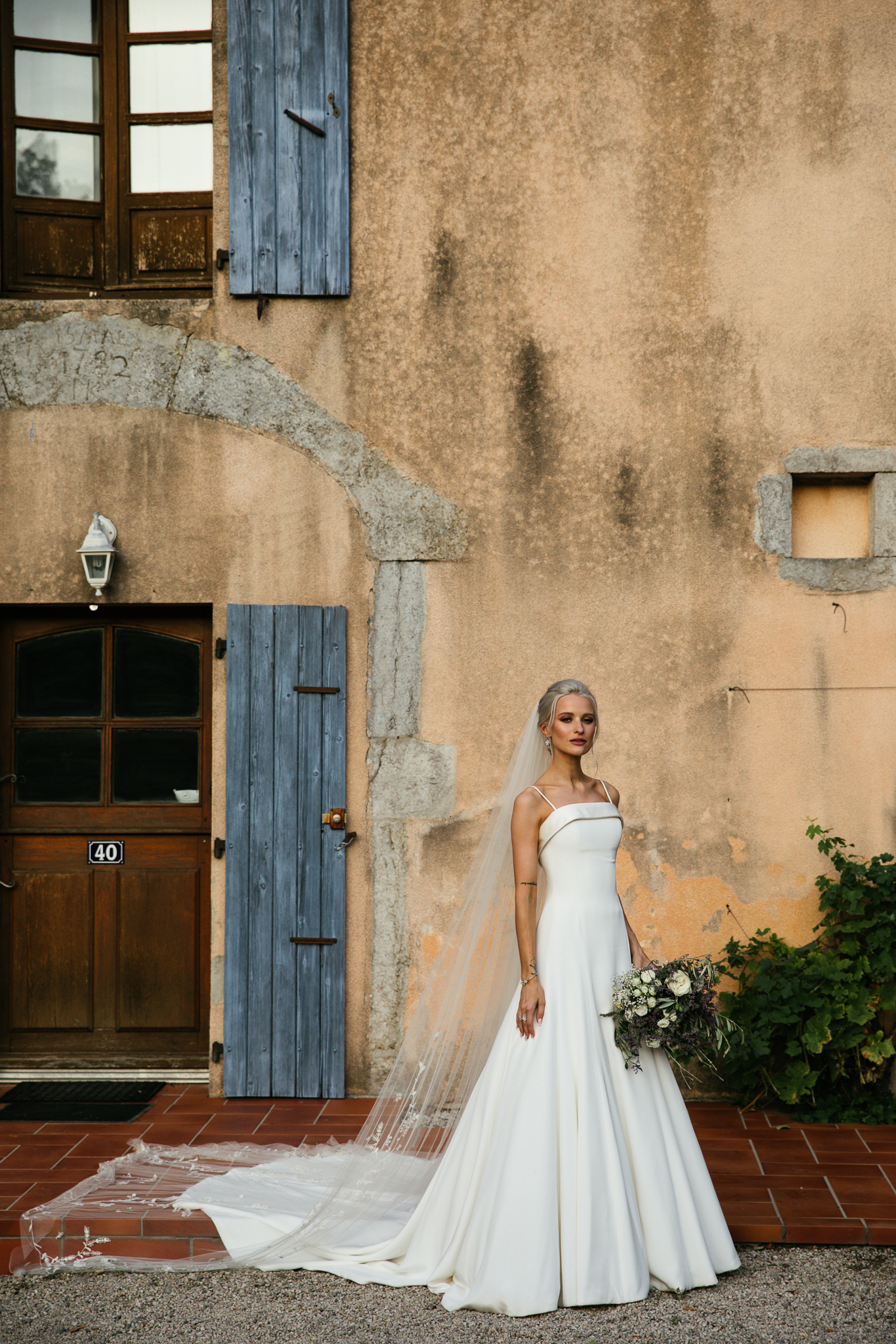 Victoria Magrath of inthefrow stands holding her wedding bouquet on her wedding day in Provence. She wears a Phillipa Lepley wedding gown.